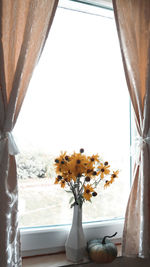 Close-up of flower vase on table by window at home