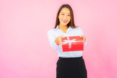 Portrait of a smiling young woman against pink background