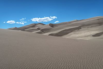 Sand dune in desert against blue sky