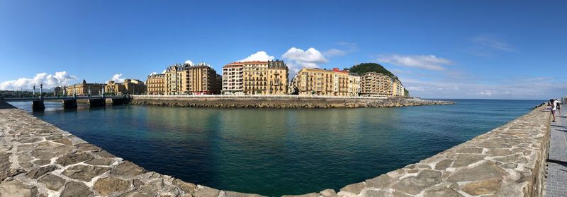 Buildings by sea against sky in city