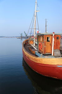 Sailboats moored at harbor against clear blue sky