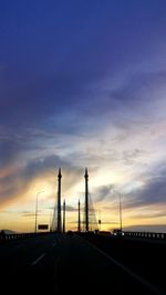 Road by silhouette bridge against sky during sunset