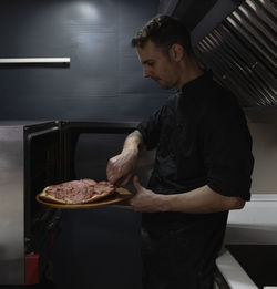 Chef takes the hot pizza out of the oven freshly baked