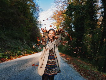 Woman standing on road against trees