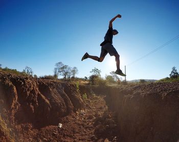 Full length of man jumping against clear sky