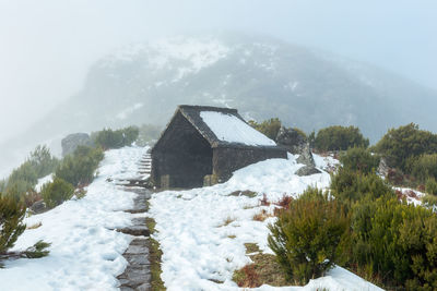 House on snowcapped mountain against sky