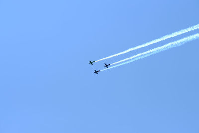 Low angle view of airshow against clear blue sky