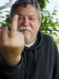 Portrait of senior man showing obscene gesture