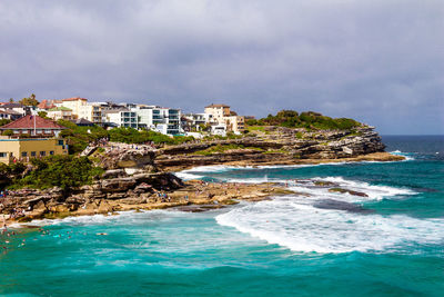 Scenic view of sea by buildings against sky