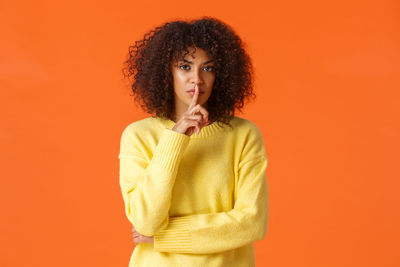 Portrait of woman against orange background