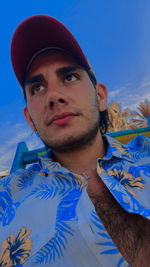 Portrait of young man standing against blue sky