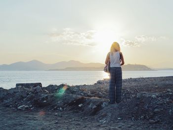 Woman standing on rock by sea