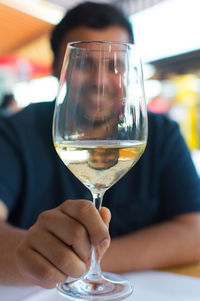 Smiling man holding wineglass while sitting at table