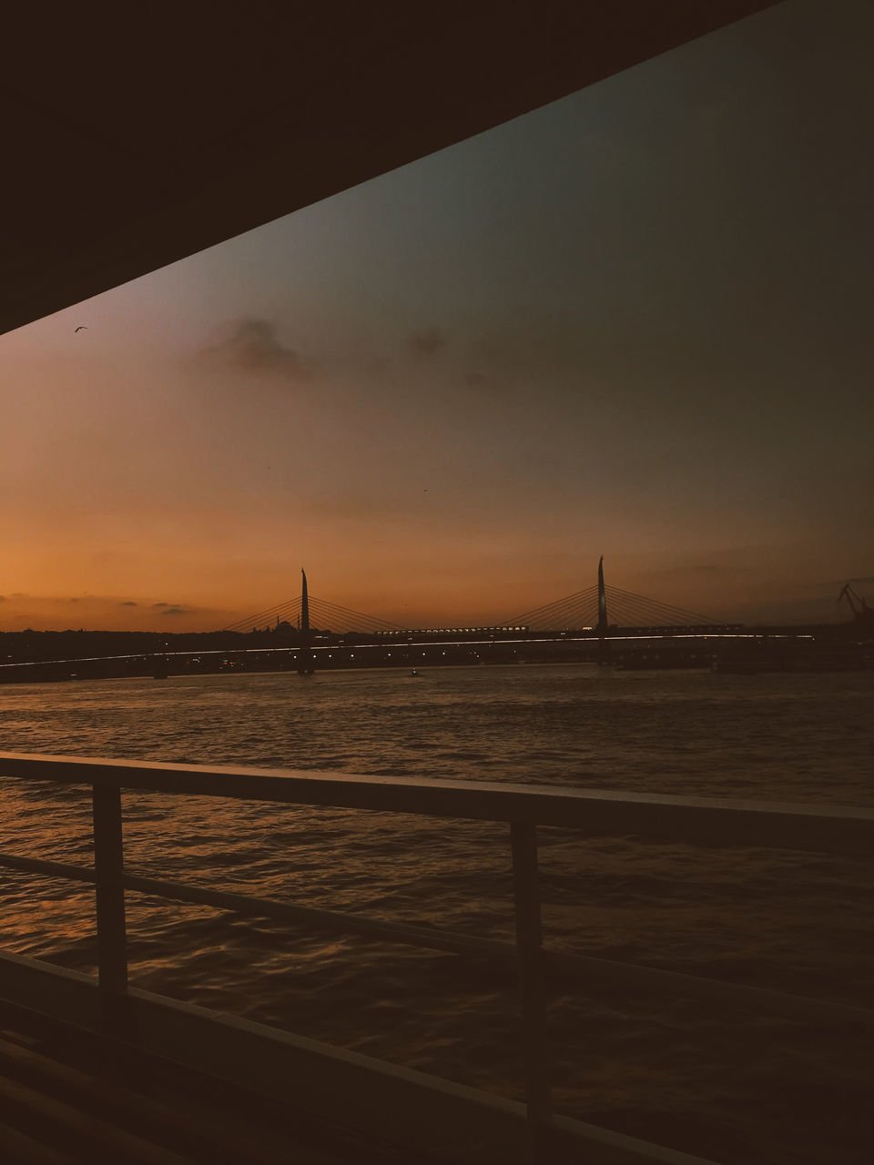 VIEW OF BRIDGE OVER SEA AGAINST SKY DURING SUNSET