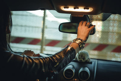 Side view of woman adjusting rear-view mirror in car