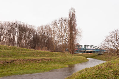 Bridge over river amidst field against clear sky