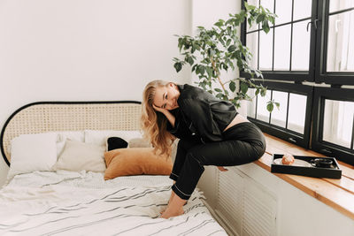 Woman sitting on bed at home