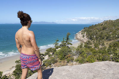 Rear view of shirtless man standing on beach