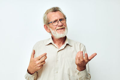 Portrait of senior man gesturing against white background