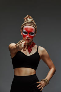 Portrait of young woman standing against black background