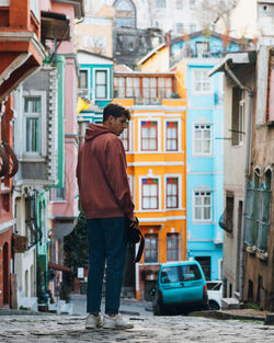 Rear view of man standing on street against buildings