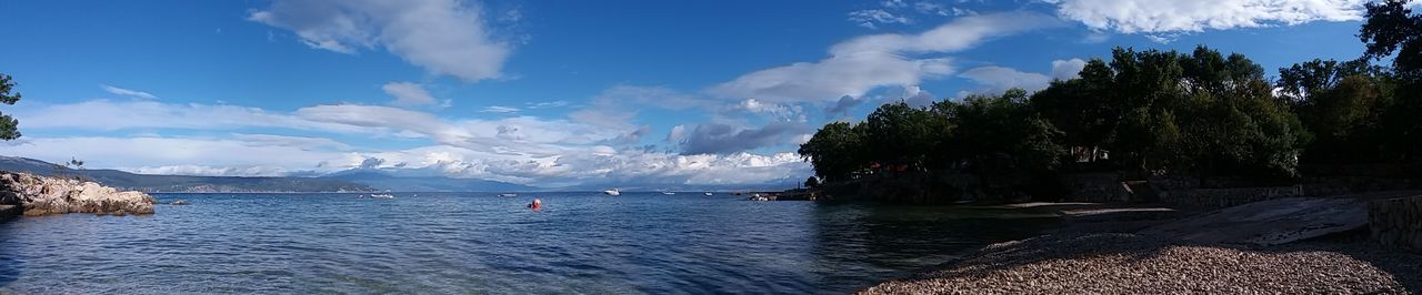 Panoramic view of sea and mountains against blue sky