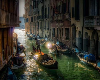 Boats moored in canal amidst buildings