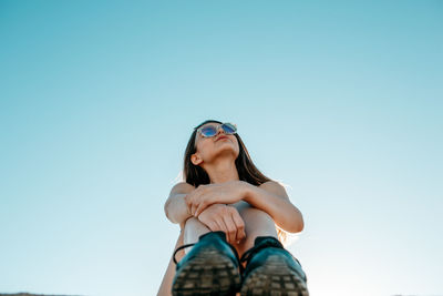 Low angle view of woman standing against clear blue sky
