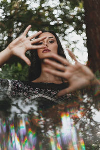 Portrait of woman holding mobile phone while standing on tree