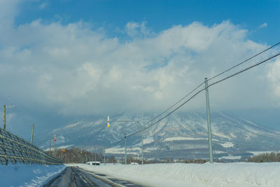 Road by snow covered mountain against sky