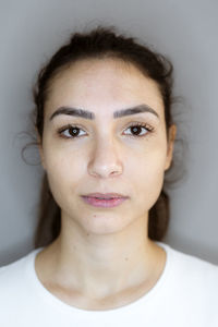 Young woman staring while standing against gray background