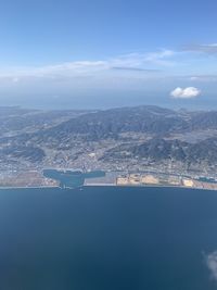 Aerial view of city by sea against sky