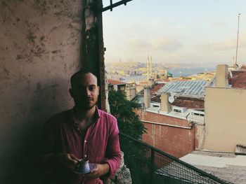 Portrait of man drinking coffee while sitting by window