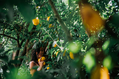 Low angle view of woman with fruits growing on tree