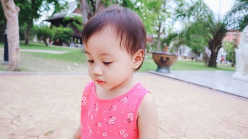 Portrait of charming little girl with pink dress looking down.