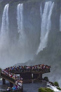 People on shore against waterfall