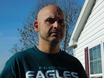 Low angle portrait of bald man by house during sunny day