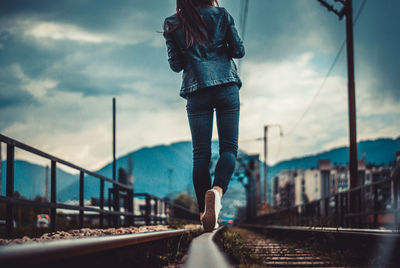 Low section of man standing on bridge in city against sky