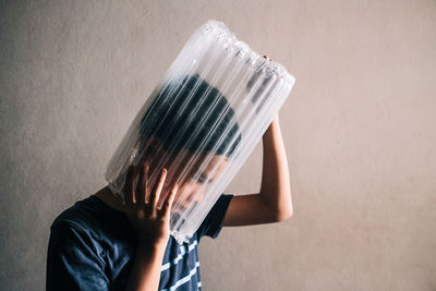 Midsection of person holding paper against wall