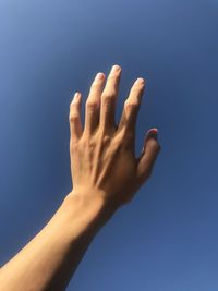 Close-up of hand against blue sky