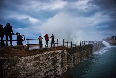 People standing by railing against sea