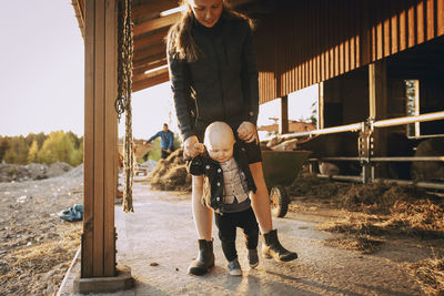 Mother holding hands of son while walking in stable