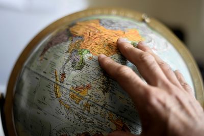 Cropped image of hand touching globe