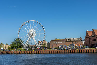 Ferris wheel in city against clear blue sky