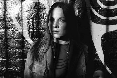 Close-up portrait of woman against graffiti wall