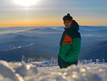 Man on snow covered mountains against sky during sunset