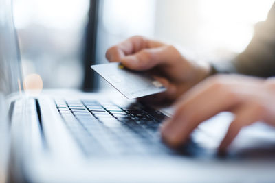 Man using laptop and holding credit card, close-up