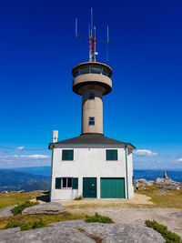 Low angle view of lighthouse by building against sky