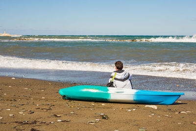 Boy on beach by sea against sky