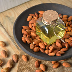 High angle view of oil amidst almonds in bowl on table